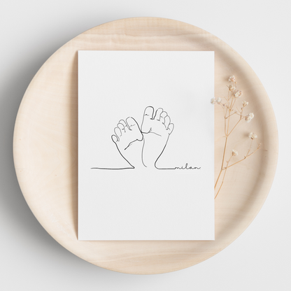 Line-Art-Poster das die zarten Umrisse von Babyfüßen zeigt. Das Design ist in minimalistischen schwarzen Linien gehalten und befindet sich auf einem weißen Hintergrund. Der Name 'Milan' ist in einer geschwungenen Schrift am unteren Rand des Posters platziert. Das Poster ist auf einem runden Holztablett arrangiert und wird von zarten Blumenakzenten begleitet.
