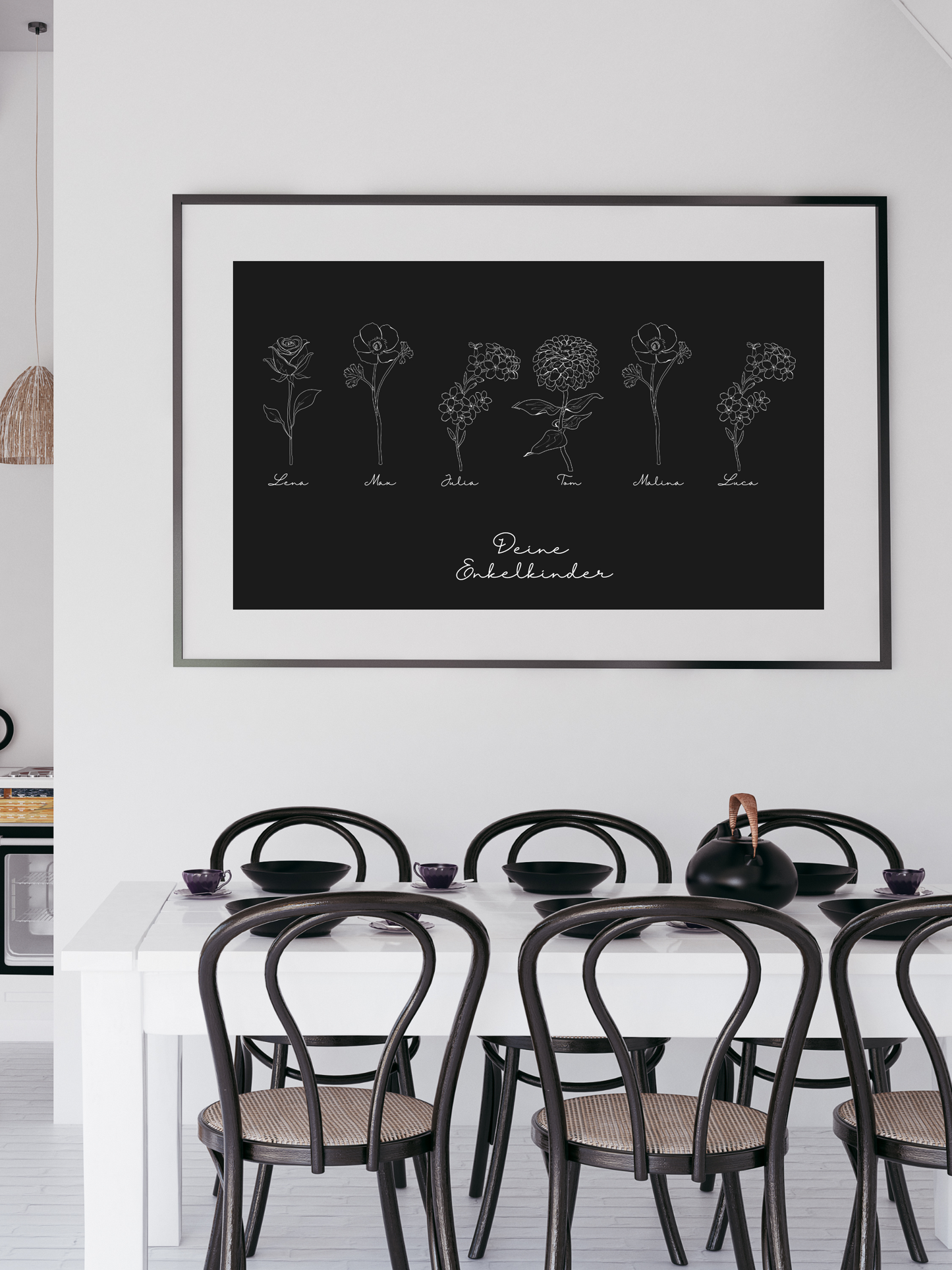 Ein großes, rechteckiges Wandbild von Sels Studio im filigranen line art-Stil hängt über einem weißen Esstisch mit schwarzen Stühlen. Auf schwarzem Hintergrund sind sieben weiße Blumenillustrationen gleichmäßig angeordnet, jede mit einem Vornamen darunter („Lena“, „Max“, „Julia“, „Tom“, „Melina“, „Lucas“). Unter den Blumen steht in zarter Handschrift „Deine Enkelkinder“. Das elegante Design und der kontrastreiche Look machen das Poster zu einem stilvollen, personalisierten Geschenk für Großeltern.
